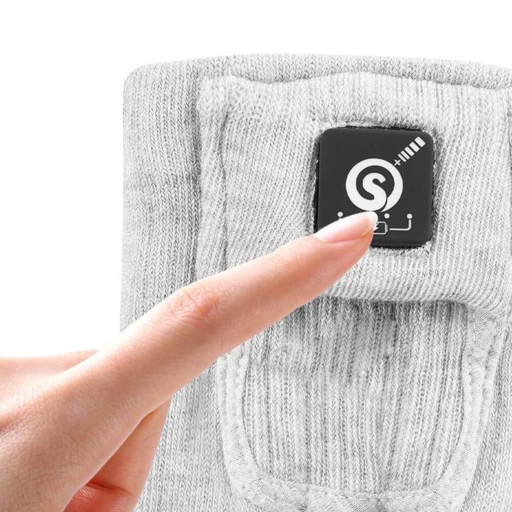 Close-up of a finger pressing the control button on Savior Heated Socks for adjusting temperature.